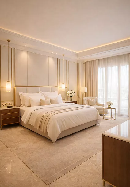 A spacious, cream-colored hotel bedroom with a plush king-sized bed, gold pendant lighting, marble flooring, and a sunlit balcony view.